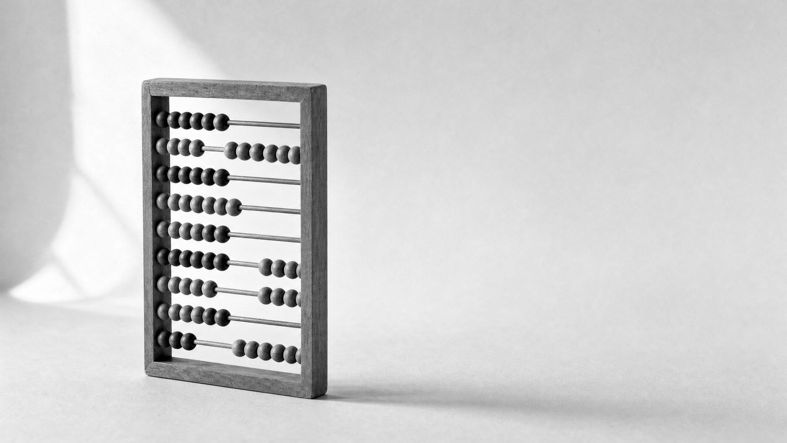A small plain wooden abacus standing upright on white paper